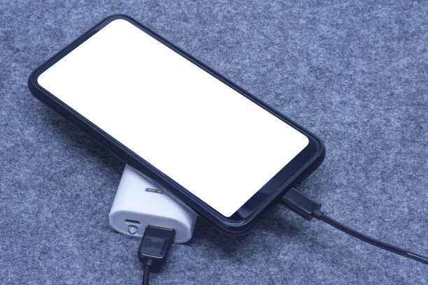 便携式充电器在灰色背景下给智能手机充电。手机模型与白色屏幕和电源银行。图片下载