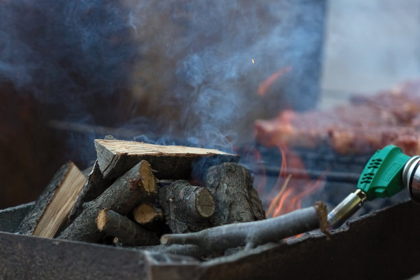 用燃气打火机点燃用来炸肉的柴火。图片下载