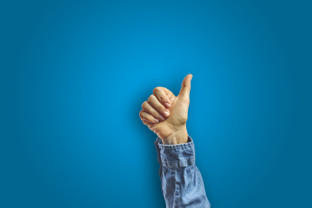 在蓝色背景下，女人的手臂做了一个ok的手势。图片下载