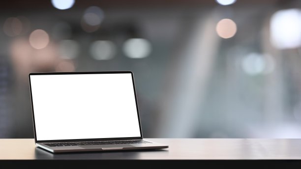 模拟电脑笔记本电脑与空白屏幕上的木桌和模糊的办公室内部背景。图片下载