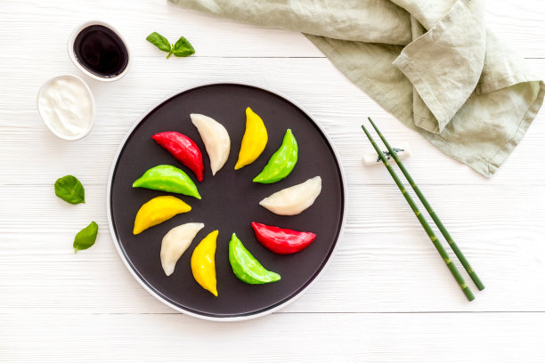 中国五颜六色的蒸饺上黑盘子，俯视图片下载