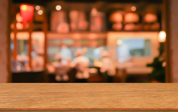 抽象模糊了酒吧餐厅的现代室内，用圆形的散景灯和现代的木桌透视来展示广告，并在背景上推广内容或产品图片下载