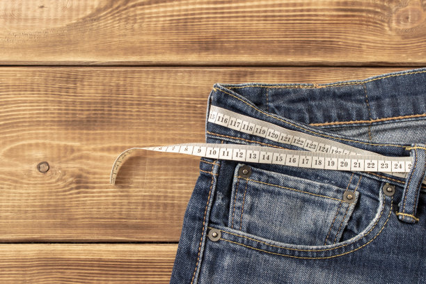 在木制背景上测量牛仔裤的重量。超重的概念。有选择性的重点。图片下载