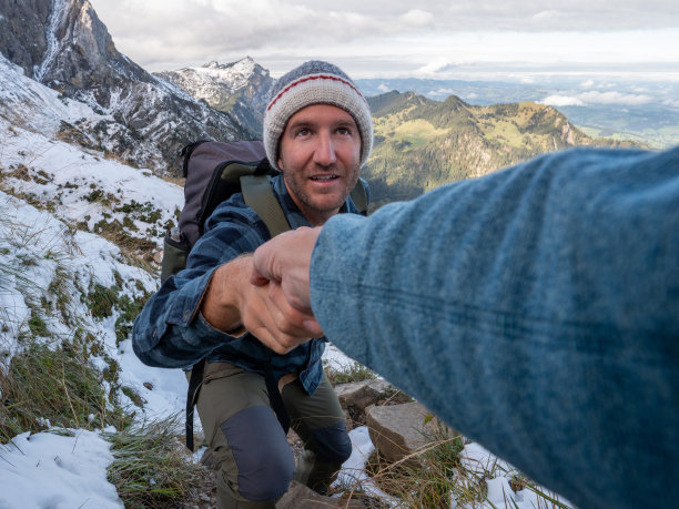 帮助队友攀登山脊岩石的徒步者图片下载