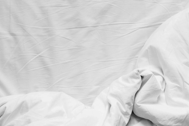 顶视图的白色棉皱巴巴的床单和皱巴巴的毛毯与复印空间图片下载