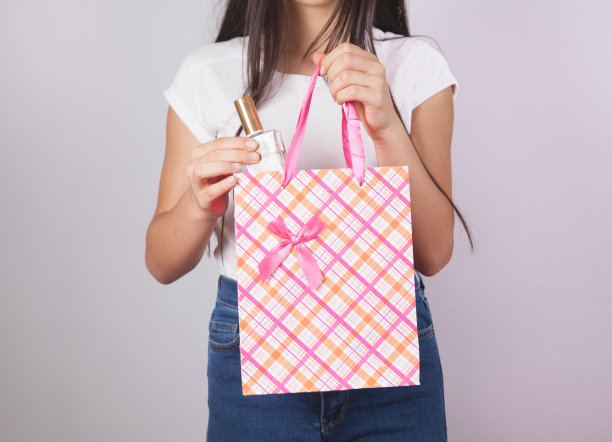 女孩从纸袋里拿出香水。图片下载