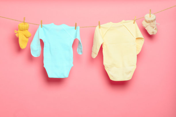 婴儿衣服在晾衣绳上粉红色的背景-图像图片下载