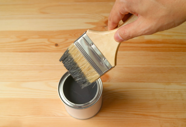 男人的手拿着油漆刷蘸油漆在木板上图片下载