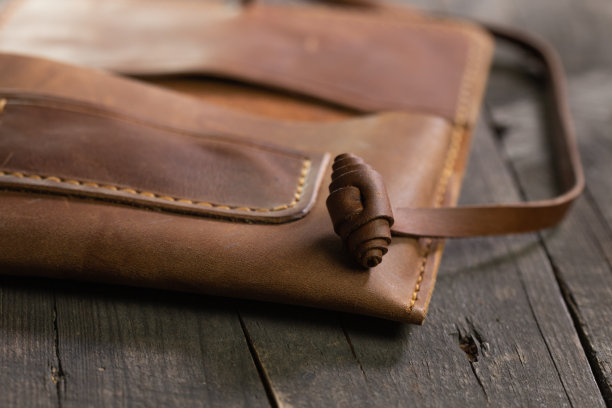 棕色时尚烟草袋皮革上的木材背景。手工制作的工艺产品。图片下载