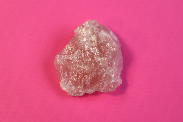 紫色背景上的一块抛光的粉色石英。最小色彩静物聚焦线窄，景深浅图片下载