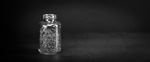 灰色背景上放着药丸的玻璃瓶。黑白风格。图片下载