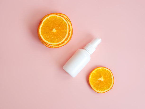 俯视图和特写的白色塑料喷瓶模型和橙色片在粉红色的背景。天然有机水疗化妆品和液体抗菌喷雾的概念。图片下载