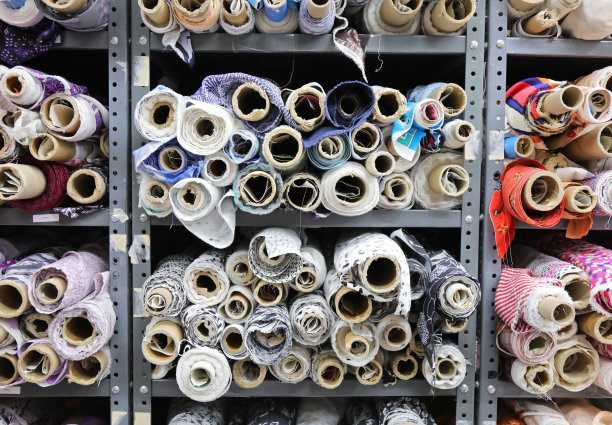 许多五颜六色的布卷堆放在商店的货架上。图片下载