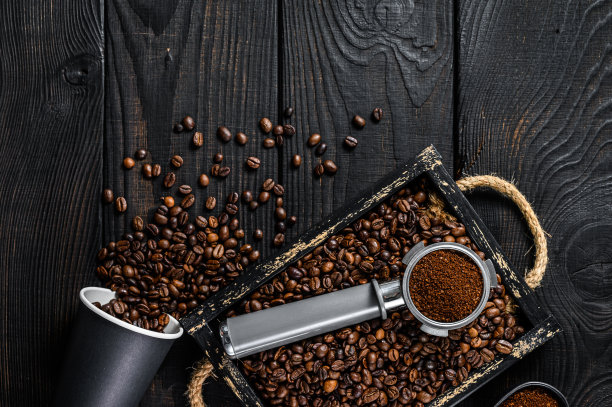 磨碎的咖啡在Portafilter为浓缩咖啡在一个木托盘与咖啡豆。黑色木制背景。前视图。本空间图片下载