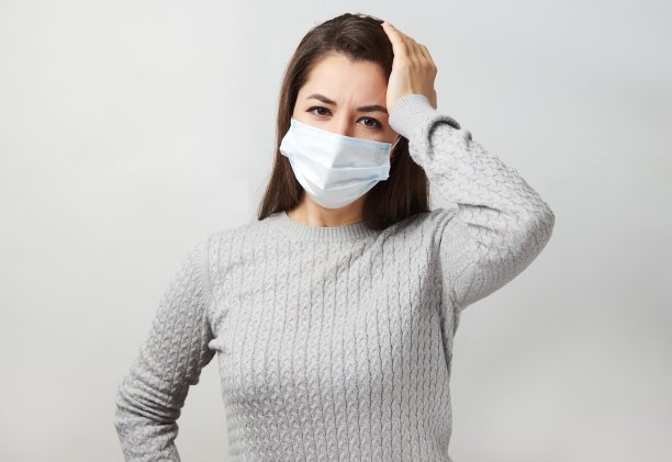 年轻女子戴着医用口罩，白色背景。图片下载