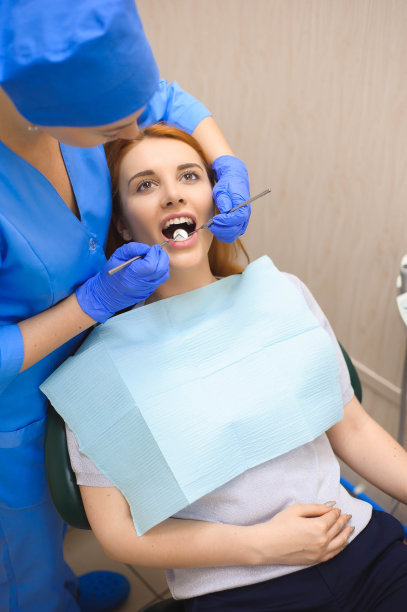 穿制服的医生在牙科诊所为女病人检查牙齿。图片下载