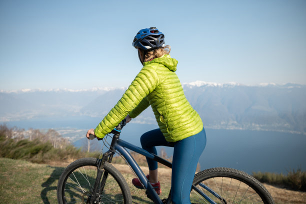 站在山顶欣赏风景的女性山地自行车手图片下载