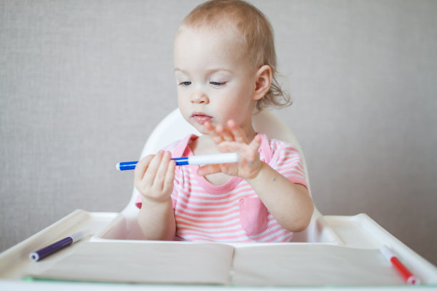 一个小女孩带着愉悦和兴趣试着用毡头笔画画图片下载