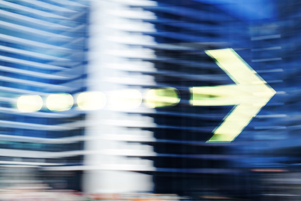 模糊的办公楼和绿箭。图片下载