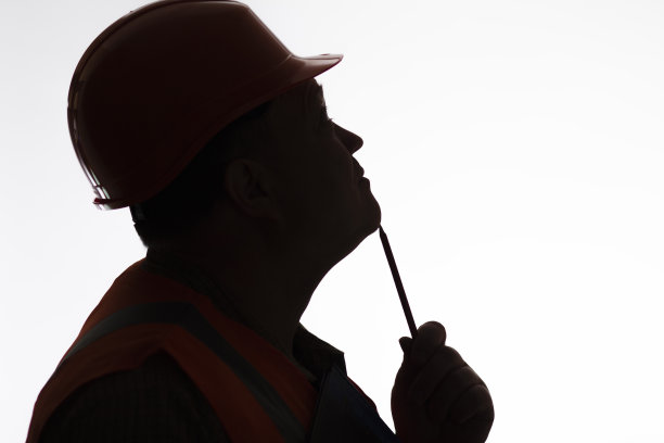 剪影思考建筑工人的侧面在白色的安全帽上孤立的背景，建筑行业的概念图片下载