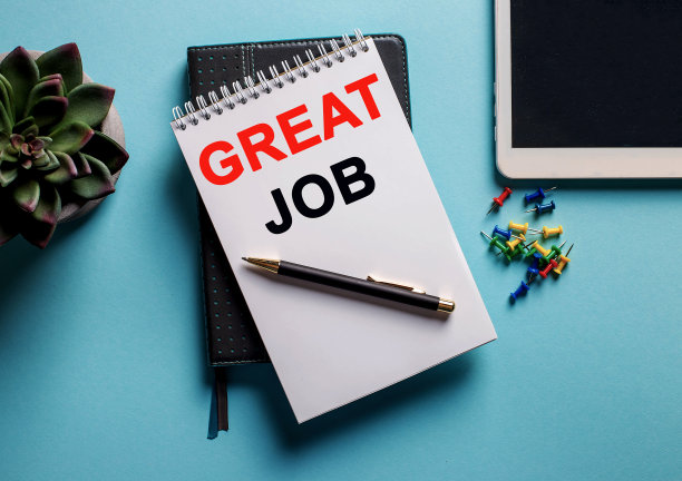 在花盆里的一朵花旁边的蓝色背景上，有一个写字板和明亮的回别针，上面写着“伟大的工作”图片下载