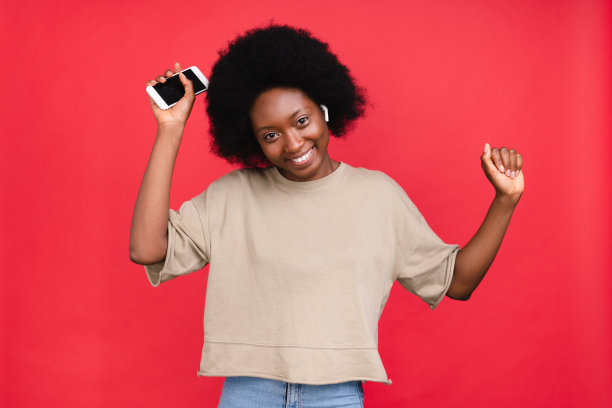 欢快的非洲女孩跳舞的音乐在她的耳机孤立在红色背景图片下载