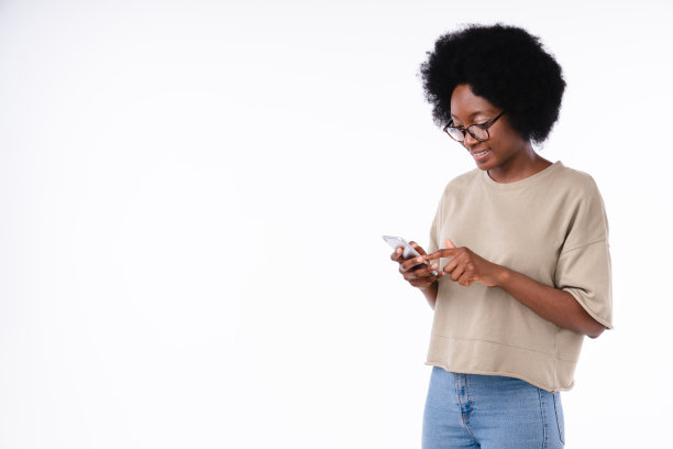 快乐开朗的非洲女孩使用智能手机孤立在白色背景图片下载