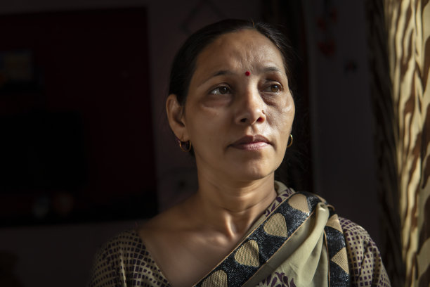 身着纱丽的安详的印度妇女站在窗边沉思着。图片下载