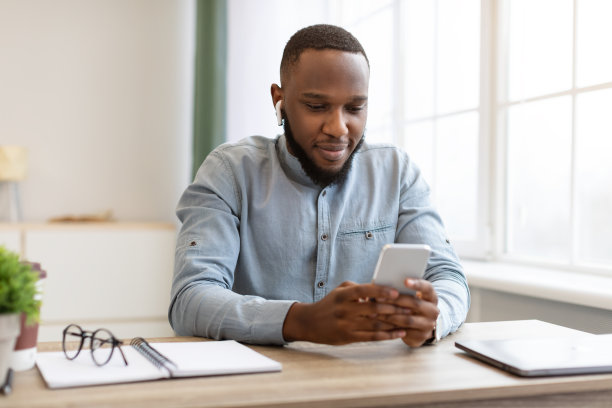 非洲商人在现代办公室里用手机戴耳机图片下载