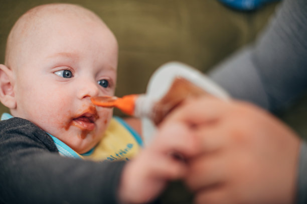 男婴很邋遢，从袋子和勺子里吃东西图片下载