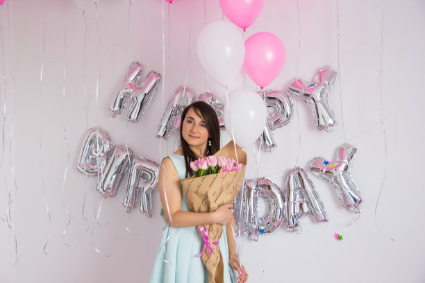 一个女人站在用气球和五彩纸屑装饰的生日派对上图片下载