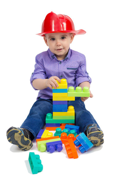 那孩子坐在地板上，两腿之间摊着玩具。孤立的图片下载