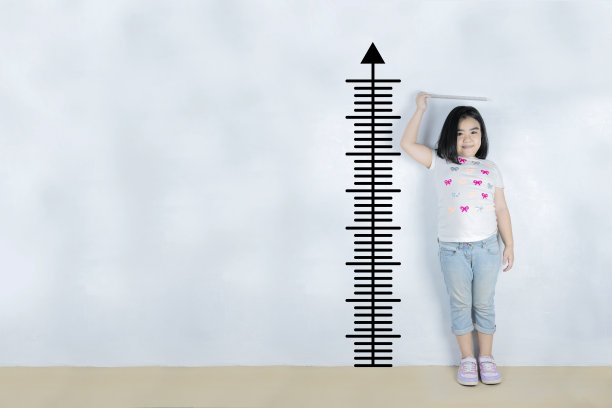 小女孩在白墙附近测量高度图片下载