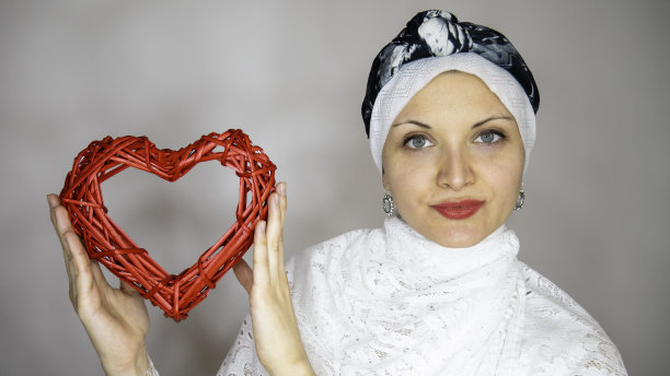 身穿白色衣服的穆斯林妇女手捧红色木制爱心，爱 Concept图片下载