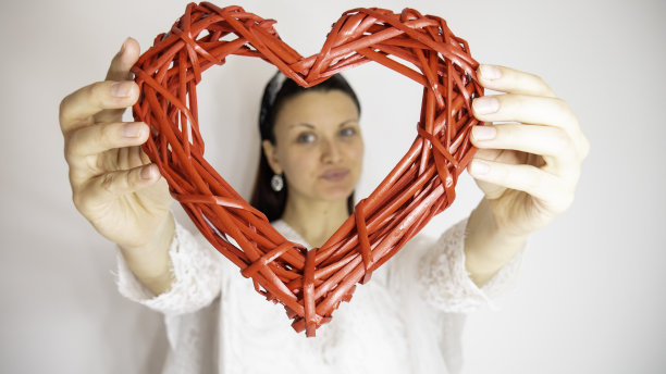 一个女人拿着一颗木制的红心。庆祝情人节。图片下载