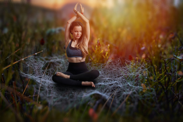 年轻的瑜伽女孩坐在带着露珠的蜘蛛网上图片下载