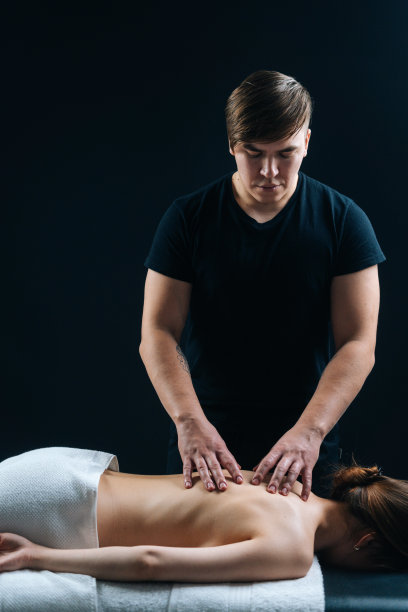 男按摩师按摩年轻女子躺在按摩台上，推着脊椎图片下载