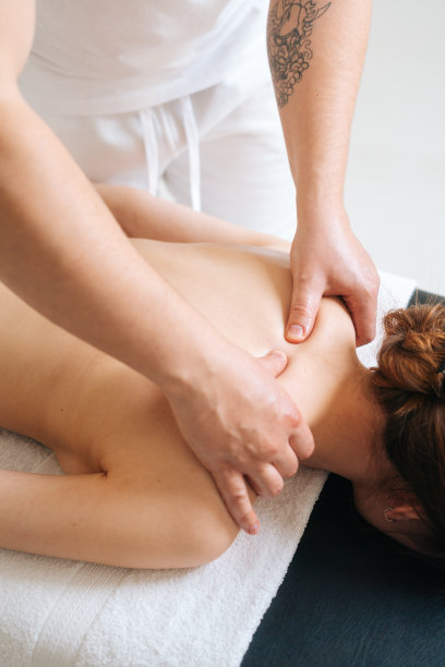 男按摩师用强有力的双手专业地为女性客户按摩肩胛骨和肩膀。图片下载