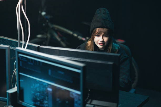 不墨守成规的少女黑客女孩使用她的电脑攻击公司服务器。女黑客喝咖啡图片下载
