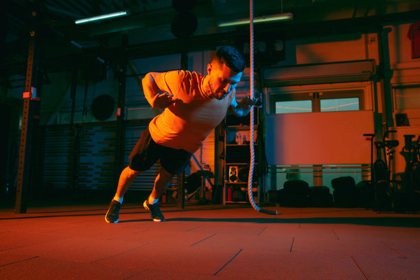 年轻的运动员，健身教练在混合霓虹灯光下训练。图片下载