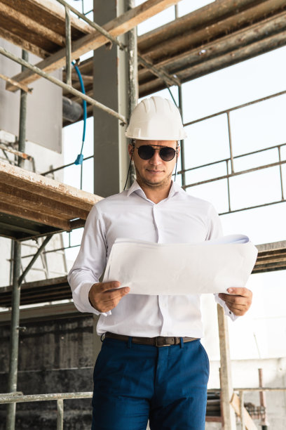 建筑工地上戴着安全帽、拿着设计图的建筑师或商人图片下载