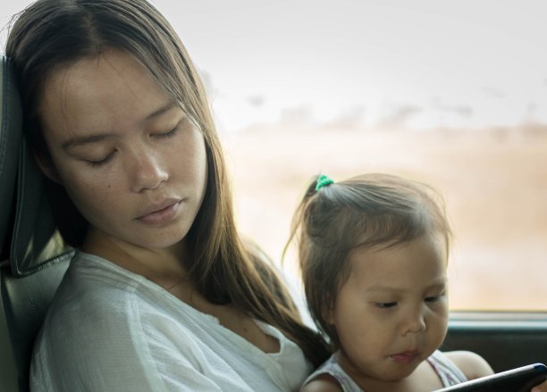 一位疲惫的母亲和她的孩子在打盹。睡眠不足。图片下载