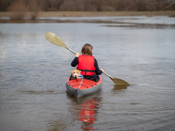 一个女孩带着一只狗在红色皮划艇上游向远处图片下载