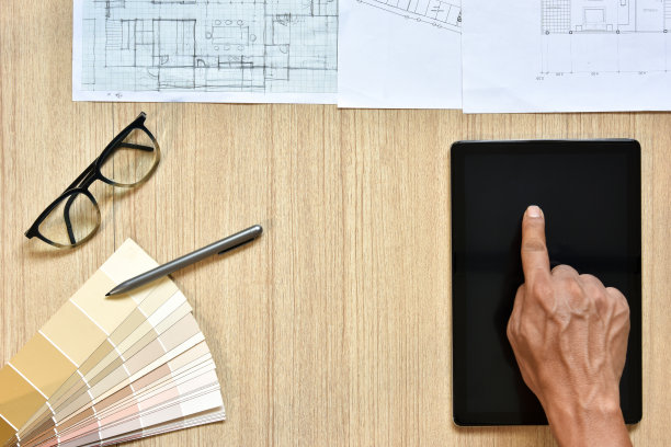 建筑师工作台的俯视图，用手触摸设备，用钢笔在木桌上勾画想法，现代技术的概念是用写字板进行建筑工作图片下载