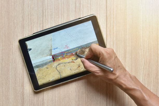 用数字笔在木桌上展示建筑图纸设计细节的手绘板，数字笔工作的新技术概念图片下载