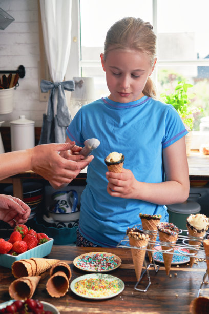准备甜筒冰淇淋的小女孩，有各种浇头、水果和糖果图片下载