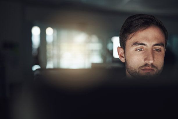 这是一个年轻的商人晚上在现代办公室里使用电脑的照片图片下载