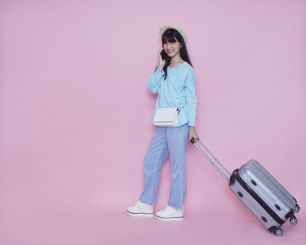 女人提着行李箱，用彩色背景打电话图片下载