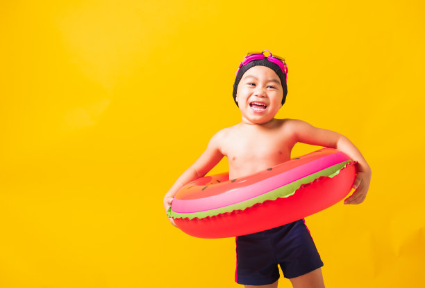 小男孩戴着护目镜和泳衣拿着沙滩西瓜充气圈图片下载
