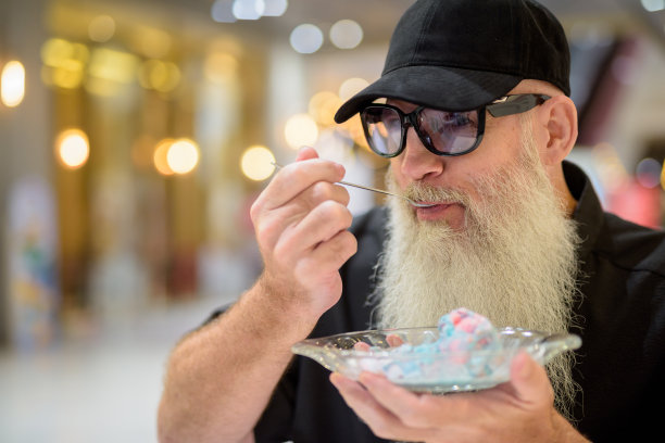 男子坐在购物中心吃冰淇淋的特写镜头图片下载